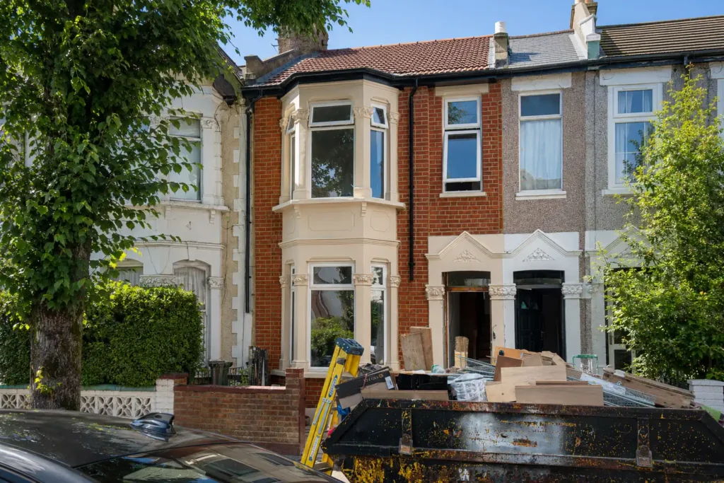 Terraced house exterior renovation in London with brickwork restoration, bay window repairs and building skip by AJ Contractors Builder